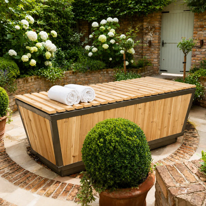 Outdoor cold plunge tub beside a garden for contrast therapy after a sauna session.