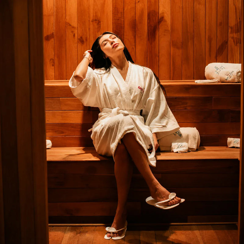 Girl relaxing inside a traditional wooden sauna during a heat therapy session.
