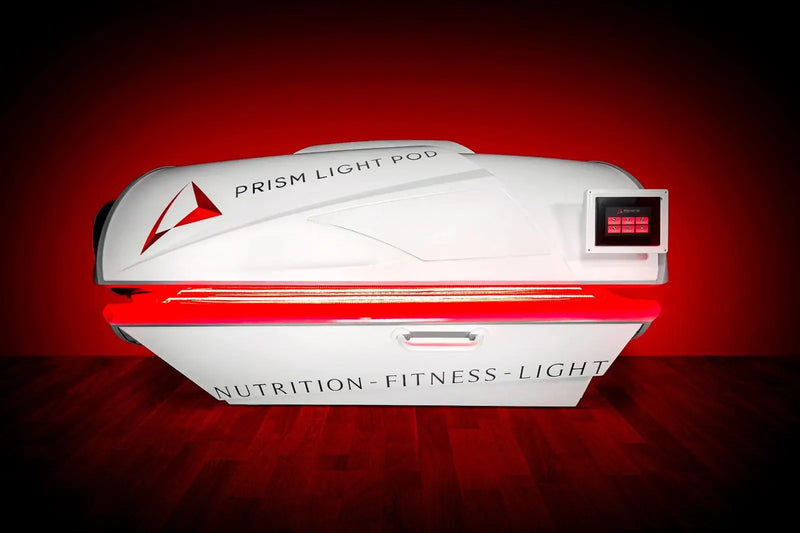 A Prism Light Pod full-body red light therapy bed, lit red, photographed in a studio.